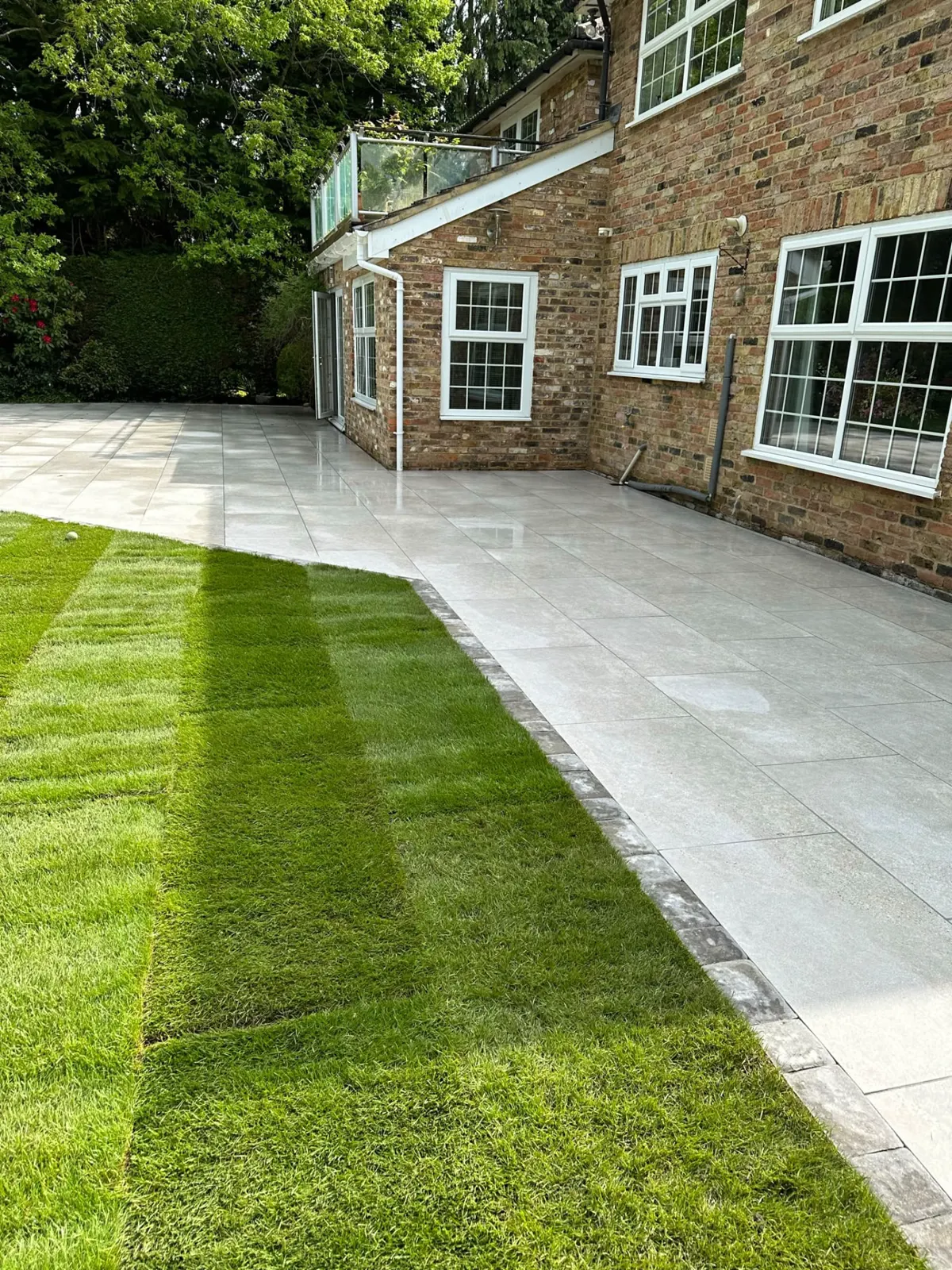 Grey porcelain wraparound patio with block edging and new turf