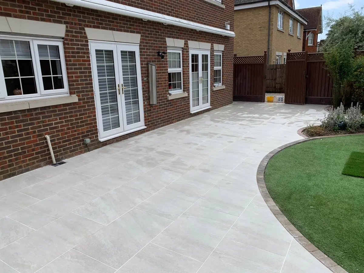 Light porcelain patio with curved block edging beside a lawn